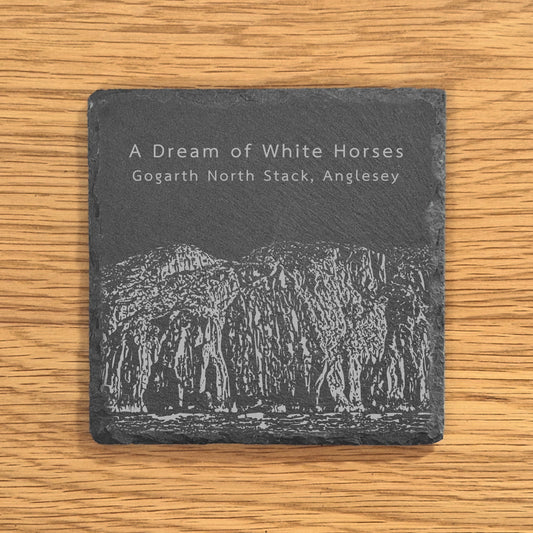 Slate coaster engraved with image of Gogarth North Stack, a popular climbing location, displayed on a wooden surface.