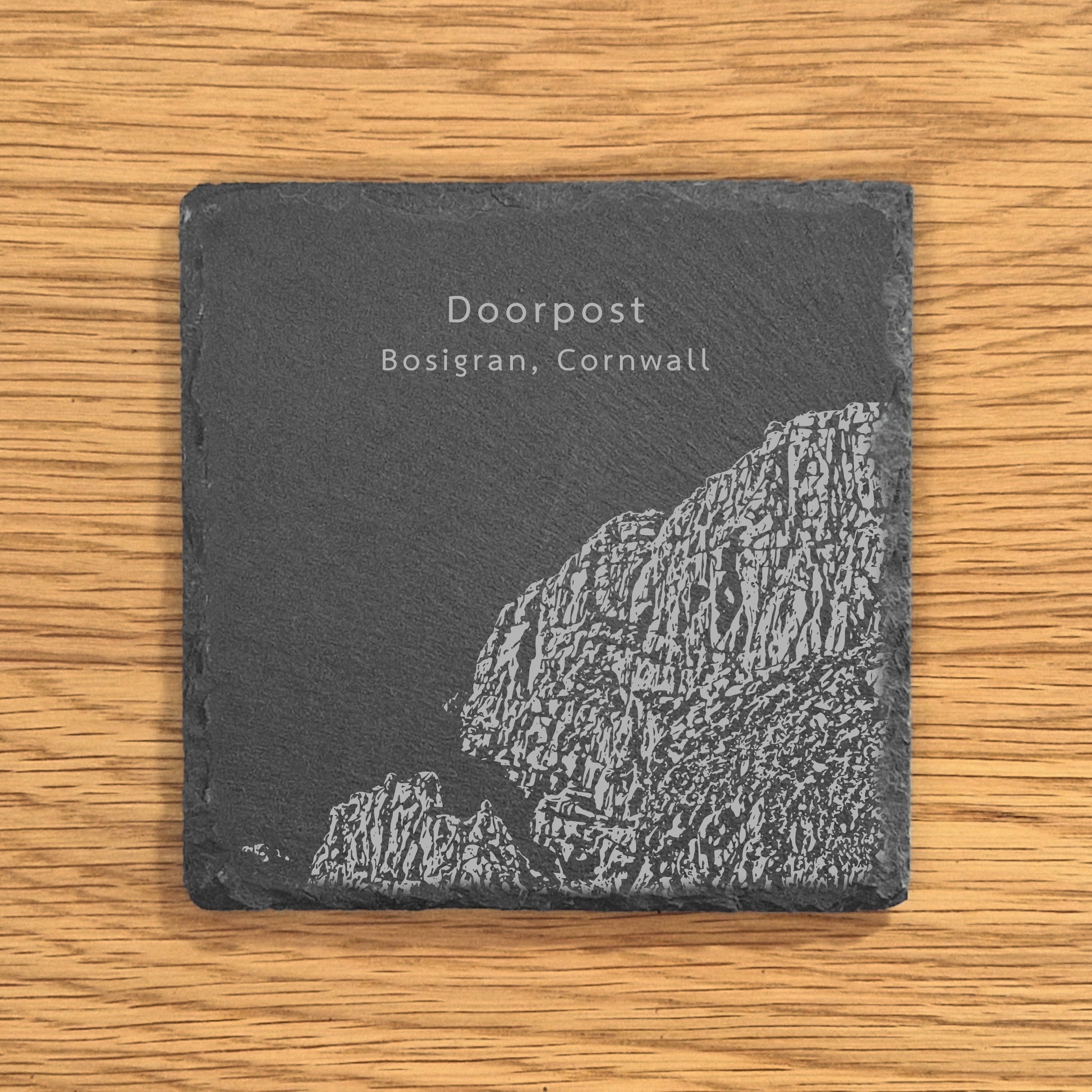 Slate coaster engraved with image of a popular climbing location, Doorpost (Bosigran, Cornwall), displayed on a wooden surface.